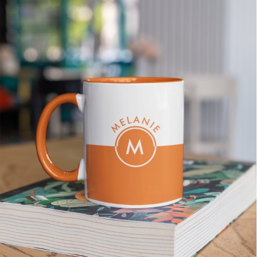 Monogramm auf weißem und orangefarbenem Trennbilds Tasse