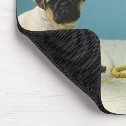 Mops Welpe sitzend auf dem Bett neben dem Telefon Mousepad (Ecke)