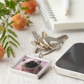 Mopshund mit Augenmaske auf dem Kopf, der auf Bett Schlüsselanhänger (Seite)