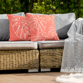 Motif aus weißem tropischem Leaf auf korallenrotem Kissen