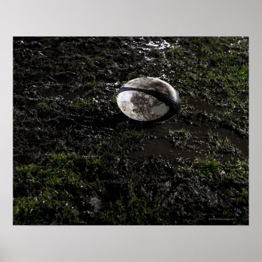 Muddy Rugby Ball sitzend auf einem zerkaut Gras Poster (Vorne)
