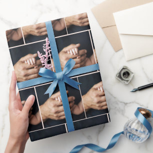 Neugeborenes Baby hält Hand in Männerhand Geschenkpapier