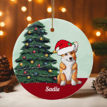 Niedliche Corgi Weihnachtsmannmütze Mit Monogramm  Keramik Ornament<br><div class="desc">Dieser wunderschöne Pembroke Walisisch Corgi Hund hat einen niedlichen Hut des Weihnachtsmanns und eine bezaubernde Kopfneigung. Der dreiseitige Jungtier sitzt vor einem hübschen Weihnachtsbaum,  der mit bunten Ornamenten geschmückt ist. Personalisieren Sie den Namen Ihres Haustieres in einem hübschen Kursiv unter dem wunderbaren zeichn meines Lieblingshündchens.</div>