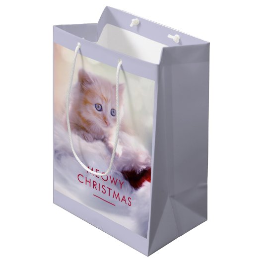 Niedliche Kittenruhe auf einer Weihnachtsmannmütze Mittlere Geschenktüte (Vorderseite Schrägansicht)