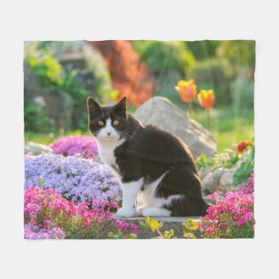 Niedliche Schwarz-weiße Katze in einem farbenfrohe Fleecedecke