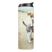 Niedliche Welpen spielen am Strand Thermosbecher (Nach links gedreht)