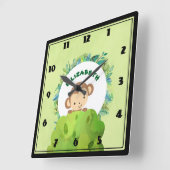 Niedlicher Affe, der sich von Hinter Bush heraushä Quadratische Wanduhr (Winkel)