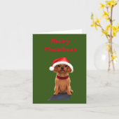 Niedlicher kleiner Hund, der eine Weihnachtsmannmü Karte (Gelbe Blume)