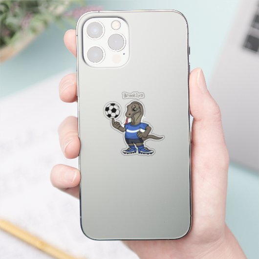 Niedlicher Komodo-Drache beim Fußballspielen Carto Aufkleber (Telefon)