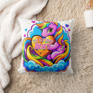 Niedliches Einhorn, das ein Herz-Kissen auf einer Kissen