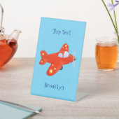 Niedliches rotes Flugzeug mit Cartoon Sockelschild (In SItu)