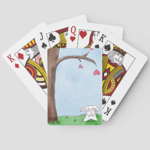 Niedliches weißes Häschen, das durch einen Baum Spielkarten