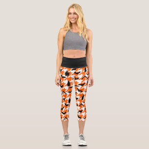 Orangefarbenes Hahnentrittmuster zwischen schwarze Capri Leggings