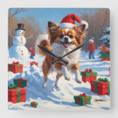 Papillon Hund läuft im Schnee mit Weihnachtshut Quadratische Wanduhr (Vorderseite)