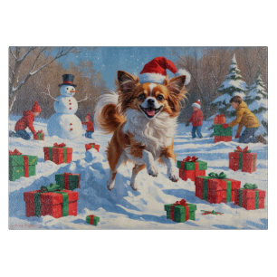 Papillon Hund läuft im Schnee mit Weihnachtshut Schneidebrett