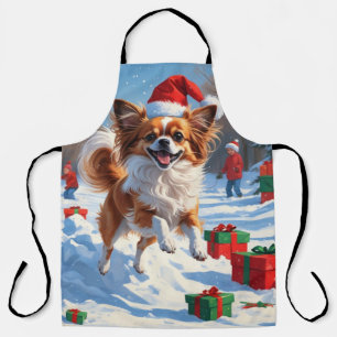 Papillon Hund läuft im Schnee mit Weihnachtshut Schürze