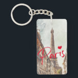 Paris Schlüsselanhänger<br><div class="desc">Dieser elegante und stilvolle Schlüsselanhänger zeigt ein Aquarellbild des Eiffelturms, das durch eine Seitenstraße zu sehen ist - und erinnert an Erinnerungen von Pariser Reisen und das französische Straßenleben! Das Wort "Paris" in leuchtend rot mit einem Herz fügt eine stilvolle und moderne Touch hinzu - Sie können diesen Text einfach...</div>