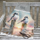 Pastel Watercolor Birds Fencepost Sunset Schürze<br><div class="desc">Soft watercolor brushwork captures two fluffy songbirds resting on weathered fence posts as a glowing sunset spreads across a dreamy countryside sky. Gentle washes of peach, blush pink, pale blue, and warm gold blend into a tranquil horizon, creating a calm pastoral atmosphere. The birds appear round and feathery, their delicate...</div>