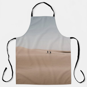PERSON, DIE BEI TAGESLICHT ÜBER BRAUNEN SAND GEHT SCHÜRZE