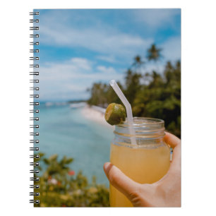 Person, die ein mit Saft gefülltes Massagegefäß in Notizblock