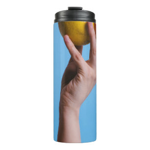 Person, die Zitrone hält Thermosbecher