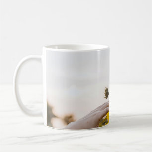 Person mit Sonnenblume Kaffeetasse