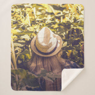 Person mit weißem Hut neben Sonnenblumenfeldern Sherpadecke