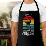 Personalisiertes Grillen und Abkühlen Schürze<br><div class="desc">Die personalisierte schwarze Schürze zeigt einen GRILLEN-Grill auf den Streifen mit den Worten "Grillen und Schillen". Perfektes Geschenk für den Tag des Vaters oder für seinen Geburtstag.</div>