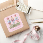 Pink Christmas Nutcracker Trio Quadratischer Aufkleber<br><div class="desc">Hübsch in Rosa! Schöner quadratischer Urlaubsticker mit einem Trio aus kunstvoll gekleideten Nussknackern stehend über Weihnachtsimmergrün und Weihnachtsbällen mit einem schönen dekorativen rosa Hintergrund. "Happy Holidays" steht ganz unten. Nutzen Sie Umschläge,  Geschenke und vieles mehr!</div>