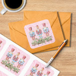 Pink Christmas Nutcracker Trio Square Sticker<br><div class="desc">Nutzen Sie diese farbenfrohen quadratischen Aufkleber auf Umschlägen,  Gastgeschenken,  Geschenken und mehr! Ein ruhmreicher rosa Hintergrund hält ein Trio von Nussknackern,  die auf Weihnachtsimmergrün stehen. Es stehen zwei verschiedene Größen zur Auswahl.</div>