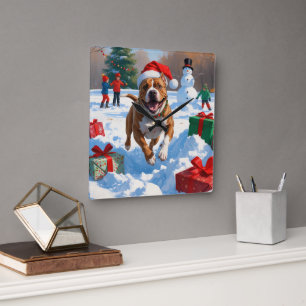 Pitbull-Hund läuft im Schnee mit Weihnachtsmütze Quadratische Wanduhr