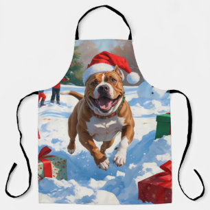 Pitbull-Hund läuft im Schnee mit Weihnachtsmütze Schürze