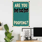 Pooping showing three black cats peeking over poster (Heimbüro)