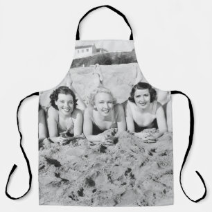 Portrait von fünf jungen Frauen, die am Strand lie Schürze