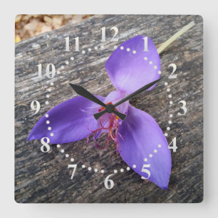 Purple flower on a bench quadratische wanduhr