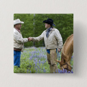 Rancher, die sich über den Zaun hinweg die Hände s Button