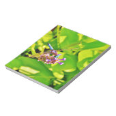 Regenbogenfarbene Libelle auf einer lila rosa Blum Notizblock (Rotiert)