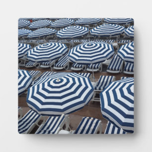 Reihen gestreifter Sonnenschirme mit Sonnenliegen Fotoplatte