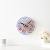 Rosa Blüten blauer Himmel. Runde Wanduhr (Zuhause)