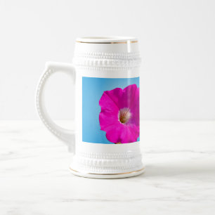 rosa Petunienblüte vor blauem Hintergrund. Bierglas