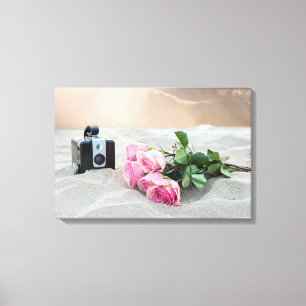 rosa Rosen im Sand mit Retro-Kamera Leinwanddruck