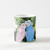 Rosa und blaue Budgien gegen den Trumpf des weißen Kaffeetasse (Mittel)