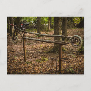 Rostige Fahrradrahmenskulptur im Wald Postkarte