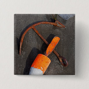 Rostiger Anker und Boje auf einem Strand Button