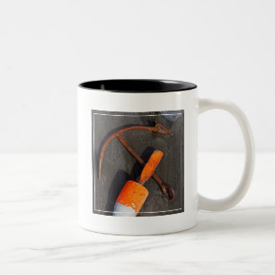 Rostiger Anker und Boje auf einem Strand Zweifarbige Tasse