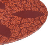 Rot verlässt Muster auf Orange Schneidebrett (Ecke)