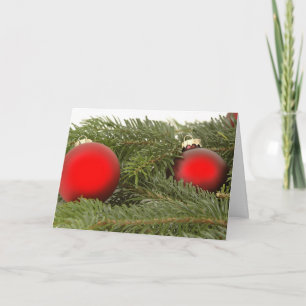 Rote Ornamente an einem Kiefernzweig-Weihnachtskar Feiertagskarte