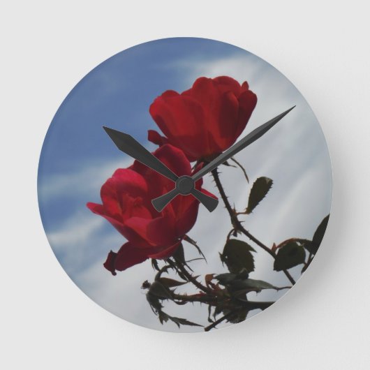 Rote Rosen gegen einen hellen blauen Himmel Runde Wanduhr (Vorderseite)