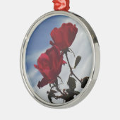 Rote Rosen gegen einen hellen blauen Himmel Silbernes Ornament (Links)