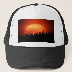 Roter Sonnenuntergang hinter schwarzem Gras Truckerkappe
